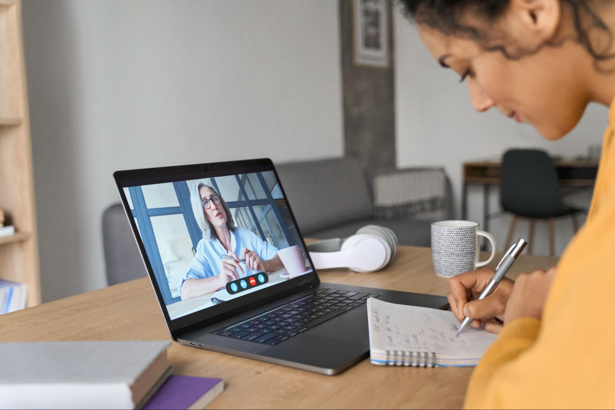 Woman taking notes during a video consultation while reviewing estate planning documents